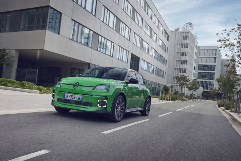 A green Renault 5 driving along a city street.